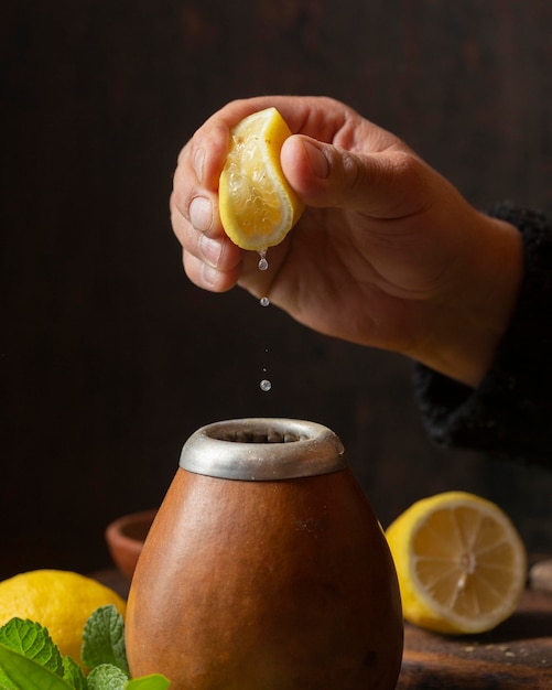 Vista frontal mano exprimiendo limón sobre té