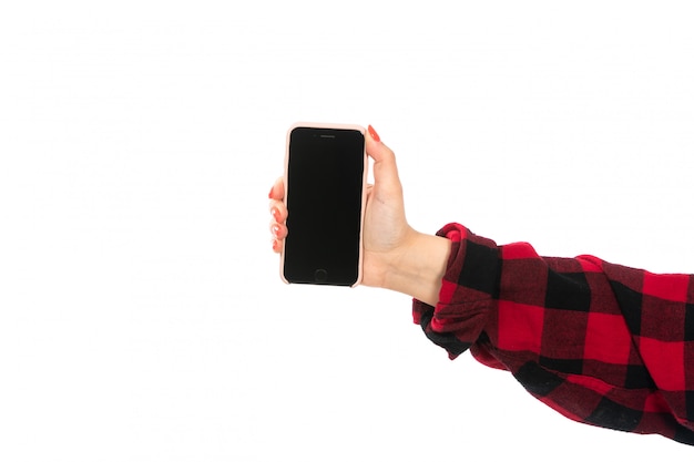 Una vista frontal mano femenina en camisa a cuadros negro-rojo con smartphone en el blanco