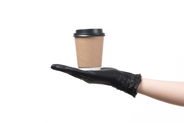 Una vista frontal mano femenina en guantes negros con taza de café sobre blanco