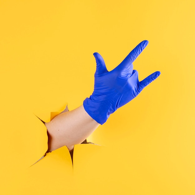 Foto gratuita vista frontal de la mano con guante quirúrgico mostrando gesto de rock and roll