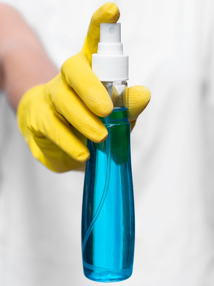 Foto gratuito vista frontal de la mano con guante quirúrgico sosteniendo una botella de alcohol