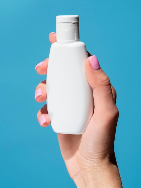 Vista frontal de la mano que sostiene la botella de desinfectante para manos