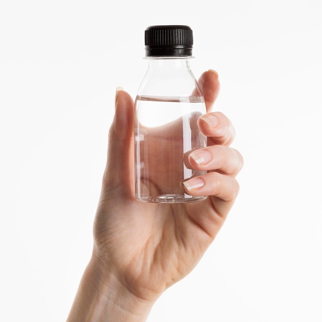 Vista frontal de la mano que sostiene la botella de líquido