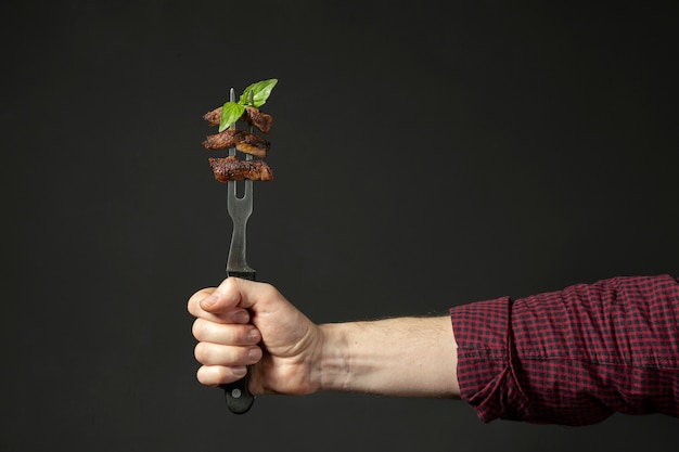 Vista frontal de la mano que sostiene la comida en el tenedor