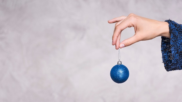 Vista frontal mano sujetando la bola de navidad