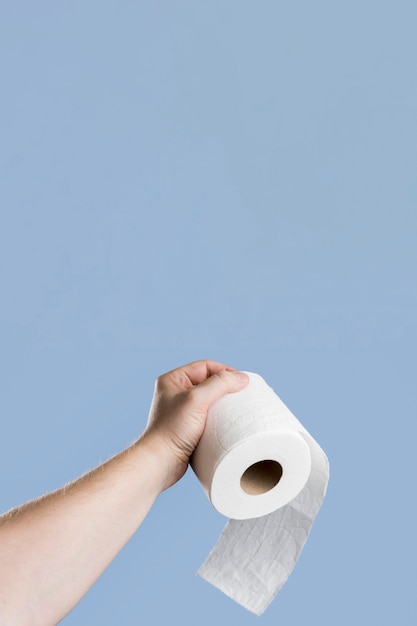 Vista frontal de la mano sujetando papel higiénico con espacio de copia