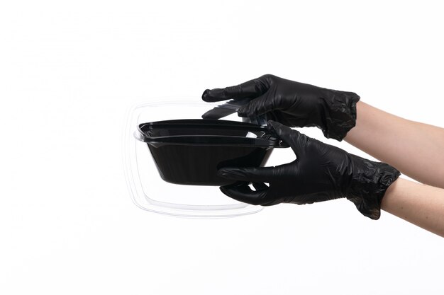 Una vista frontal manos femeninas en glvoes negros sosteniendo un tazón con comida en blanco