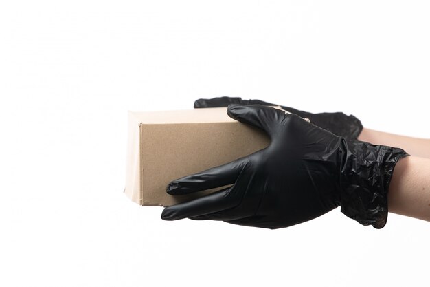 Una vista frontal manos femeninas en guantes negros con paquete de entrega en blanco
