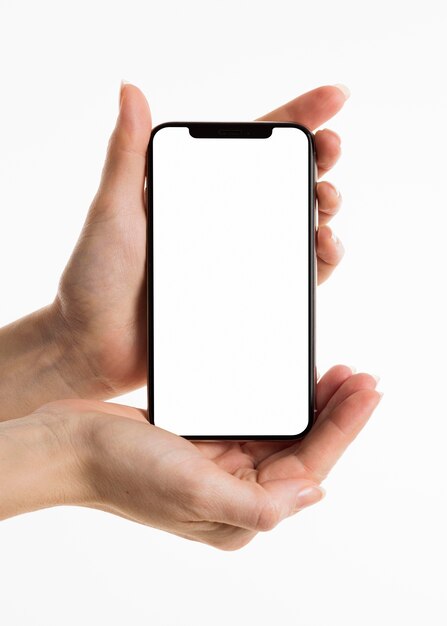 Vista frontal de manos sosteniendo smartphone con pantalla en blanco