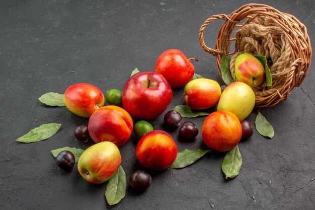 Vista frontal de manzanas frescas con ciruelas y melocotones en mesa oscura jugo maduro suave