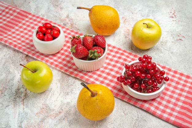 Vista frontal de manzanas frescas con frutos rojos y peras en el árbol de baya de fruta de mesa blanca