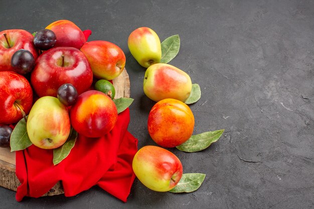 Vista frontal de manzanas frescas con melocotones y ciruelas en el árbol de jugo de mesa oscura madura suave