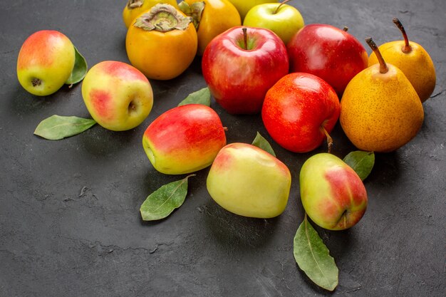 Vista frontal de manzanas frescas con peras y caquis en mesa oscura madura fresca suave