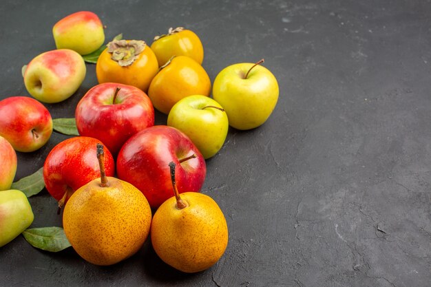 Vista frontal de manzanas frescas con peras y caquis en piso oscuro meloso maduro fresco