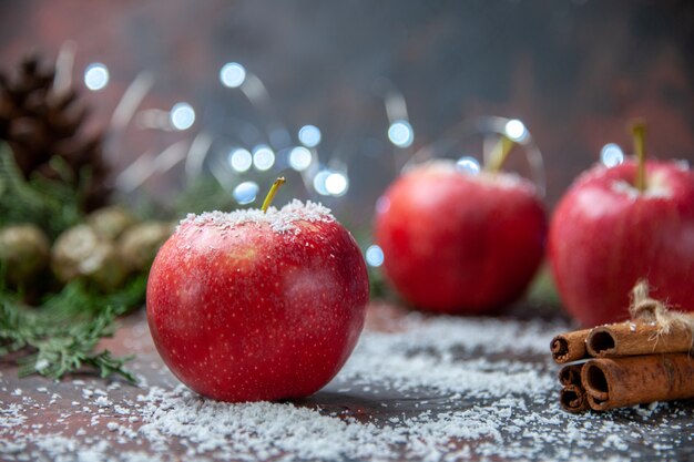 Vista frontal manzanas rojas canela palitos de coco en polvo en la oscuridad