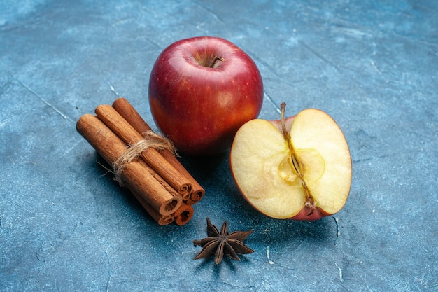 Vista frontal de manzanas rojas frescas con canela sobre superficie azul