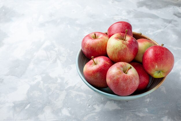 Vista frontal de las manzanas rojas frescas dentro de la placa sobre el fondo blanco fruta fresca vitamina madura suave