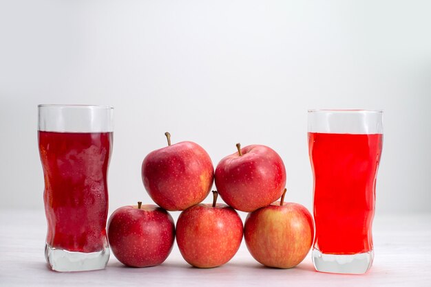 Vista frontal de manzanas rojas frescas forradas con jugos en el escritorio blanco fruta fresca planta de árbol maduro suave