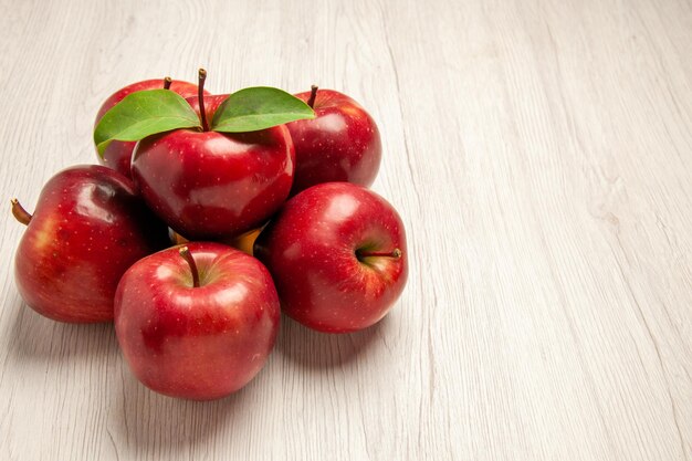 Vista frontal de las manzanas rojas frescas frutas maduras y suaves en el escritorio blanco claro color de la fruta planta fresca árbol rojo