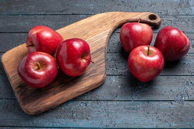 Vista frontal de las manzanas rojas frescas frutas maduras suaves en el escritorio de color azul oscuro frutas de color rojo vegetal vitamina fresca