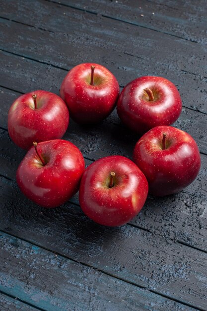 Vista frontal de las manzanas rojas frescas frutas maduras y suaves en el escritorio de color azul oscuro de frutas de color rojo vegetal vitamina fresca