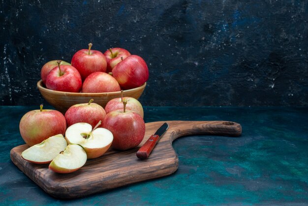 Vista frontal de las manzanas rojas frescas jugosas y suaves dentro de la placa en el escritorio azul oscuro fruta fresca vitamina suave madura