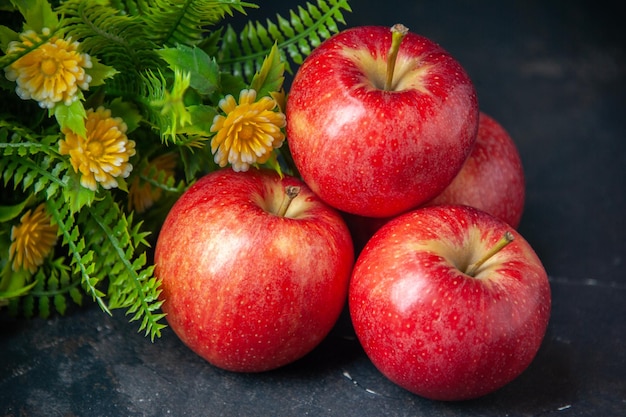 Vista frontal de manzanas rojas frescas con planta verde sobre un fondo oscuro color suave pera comida vitamina madura dieta manzana