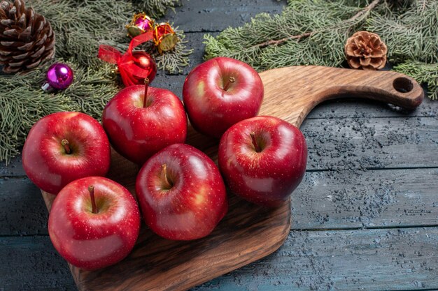 Vista frontal de las manzanas rojas frescas suaves frutos maduros en la planta de escritorio azul oscuro muchas frutas de color rojo vitamina fresca