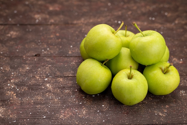 Vista frontal de manzanas verdes frescas aisladas sobre un escritorio de madera