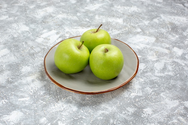 Vista frontal de las manzanas verdes frescas dentro de la placa sobre la superficie blanca fruta fresca madura suave vitamina alimentaria