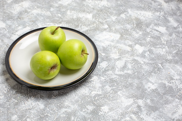 Vista frontal de las manzanas verdes frescas dentro de la placa en la superficie de color blanco claro fruta fresca madura suave vitamina alimentaria