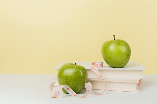 Vista frontal de manzanas verdes en libros con espacio de copia