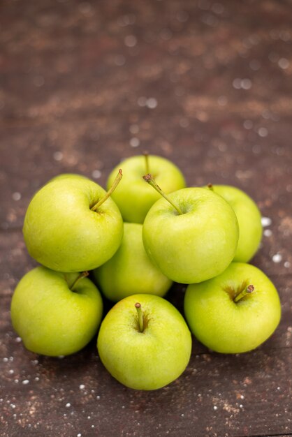 Vista frontal manzanas verdes suaves y jugosas aisladas en marrón