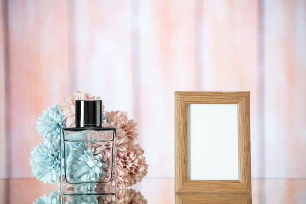 Vista frontal del marco de fotos de color marrón claro de perfume femenino flores sobre fondo borroso de madera