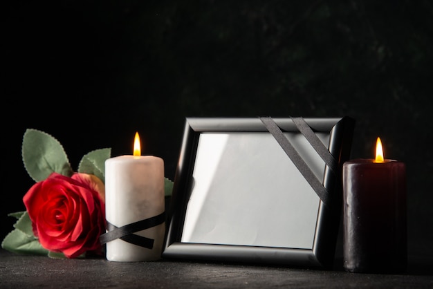 Vista frontal del marco de imagen con velas y flores en la oscuridad