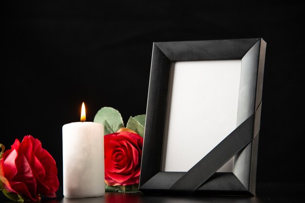 Vista frontal del marco de imagen con velas y flores rojas en la oscuridad
