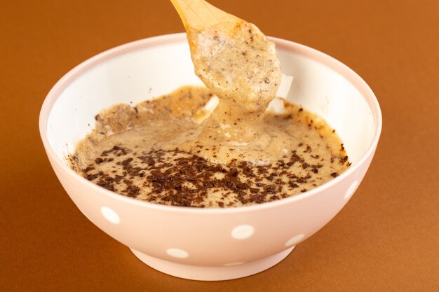 Una vista frontal marrón choco postre sabroso delicioso dulce con café en polvo dentro de un plato blanco aislado en el fondo de café con leche dulce postre refrescante
