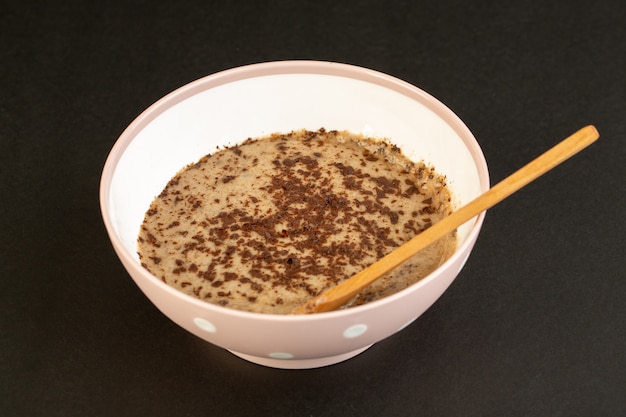 Una vista frontal marrón choco postre sabroso delicioso dulce con café en polvo dentro de un plato blanco aislado en el fondo oscuro dulce postre refrescante