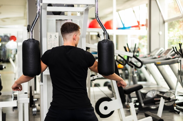 Vista frontal masculino en el gimnasio haciendo ejercicio de brazos