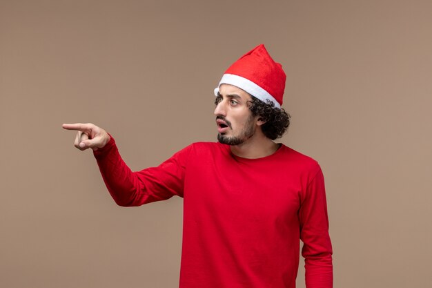 Vista frontal masculino en rojo con expresión confusa sobre fondo marrón vacaciones emoción navidad