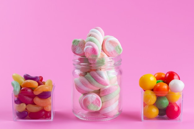 Una vista frontal masticando malvaviscos junto con coloridas mermeladas y caramelos en rosa, dulce de color caramelo