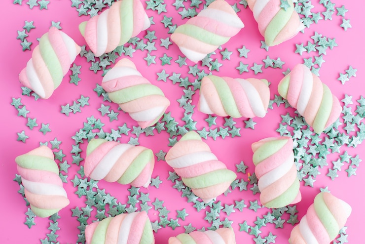 Foto gratuito una vista frontal masticando malvaviscos todo en rosa, con partículas de caramelo en forma de estrella confitura de azúcar del arco iris de color