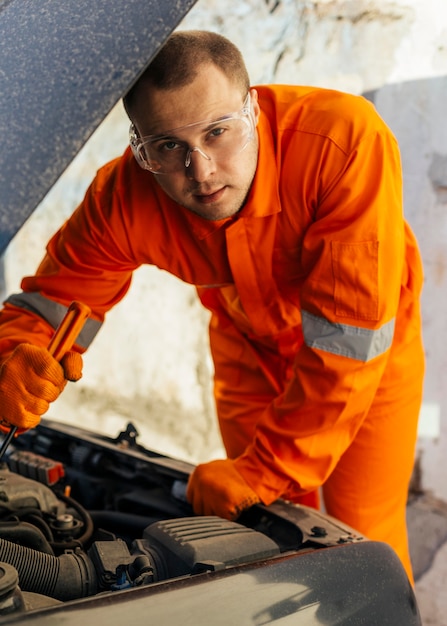 Vista frontal del mecánico con gafas protectoras y uniforme.