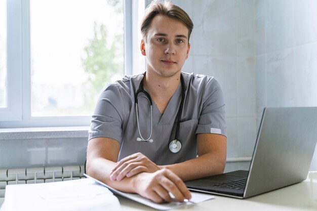 Vista frontal del médico con estetoscopio trabajando en equipo portátil