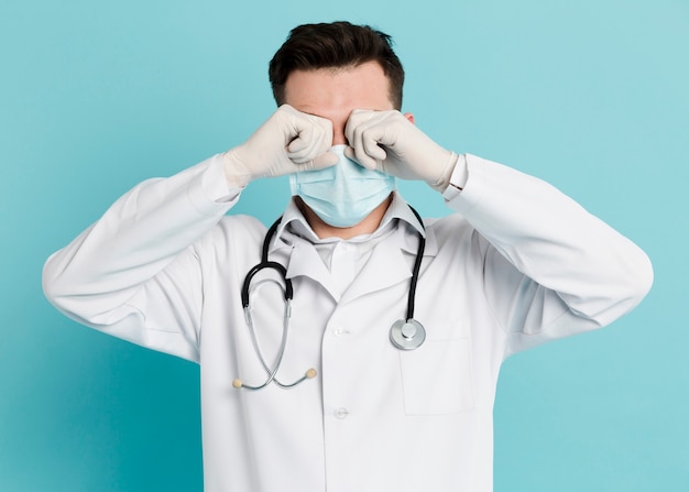 Foto gratuita vista frontal del médico con máscara médica frotando sus ojos