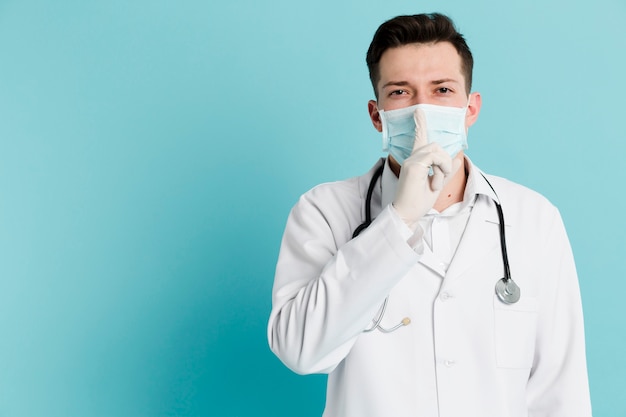 Foto gratuita vista frontal del médico con máscara médica y guantes quirúrgicos haciendo el signo tranquilo