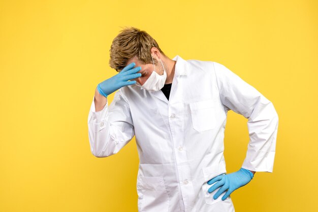 Vista frontal médico masculino destacó sobre fondo amarillo pandemia de virus covid de salud