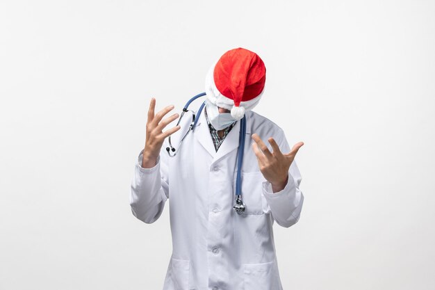 Vista frontal médico masculino con gorra roja en la pared blanca pandemia de virus covid de año nuevo