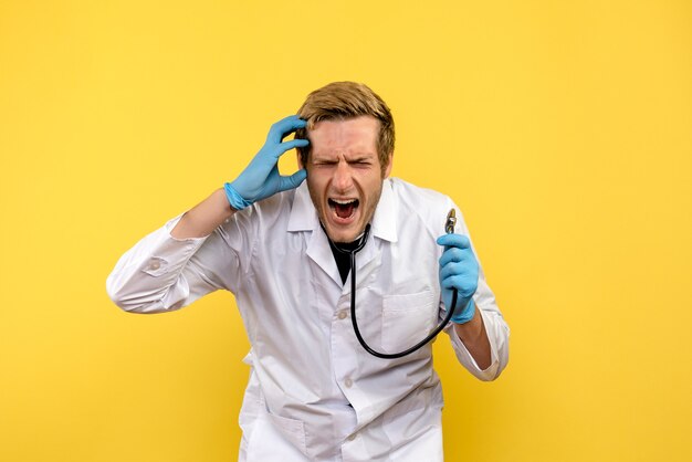 Vista frontal médico masculino gritando sobre fondo amarillo médico de virus humanos de salud