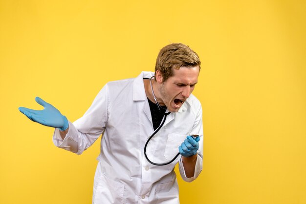 Vista frontal médico masculino gritando sobre fondo amarillo virus salud emoción médico